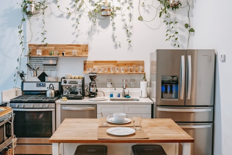 A white kitchen with wooden shelves and a wooden table